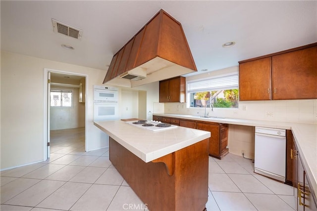 kitchen with custom exhaust hood, white appliances, plenty of natural light, and light tile patterned floors