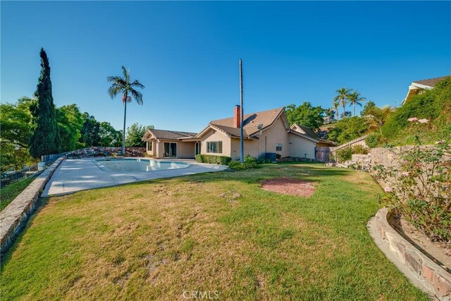 rear view of property with a yard, a fenced in pool, and a patio area