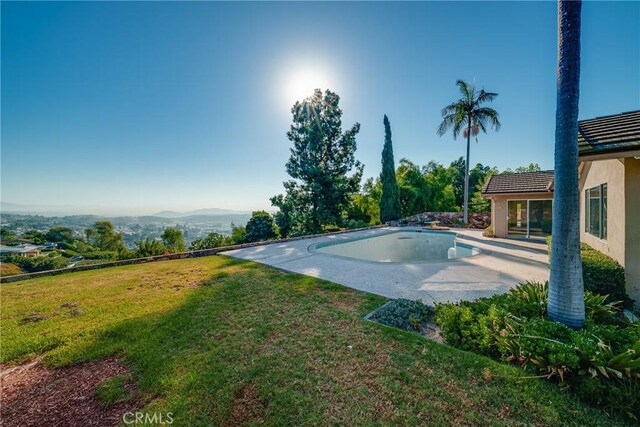 view of swimming pool featuring a lawn, a mountain view, and a patio area