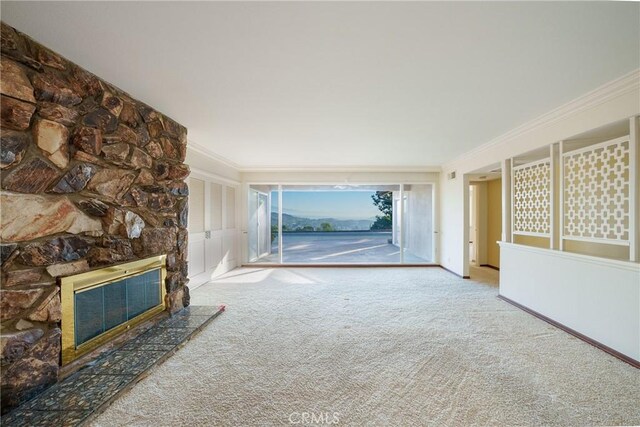 unfurnished living room featuring a fireplace, carpet floors, and ornamental molding