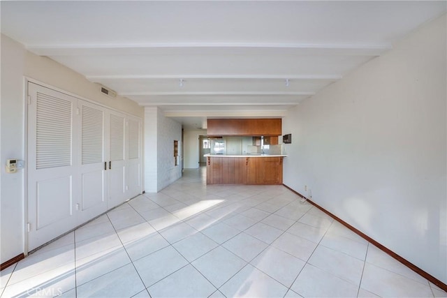 unfurnished living room featuring beam ceiling and light tile patterned floors