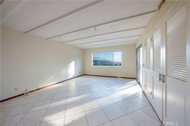 spare room with beamed ceiling and light tile patterned floors