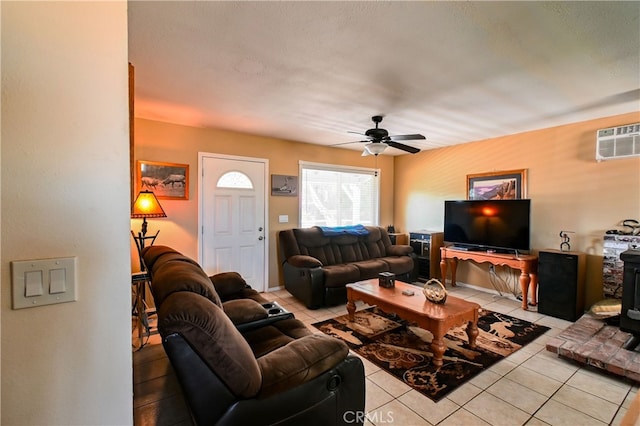 living room featuring light tile patterned floors, a wall mounted air conditioner, a wood stove, and ceiling fan