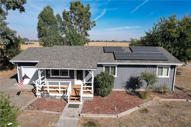 single story home with a garage, a porch, and solar panels