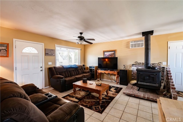 living room featuring ceiling fan, a wood stove, light tile patterned floors, and a wall mounted AC