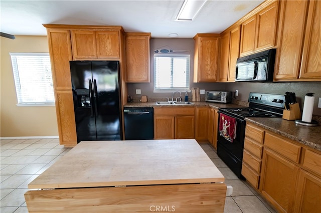 kitchen featuring light tile patterned flooring, black appliances, sink, and a kitchen island