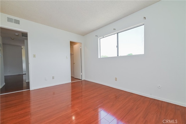 unfurnished room featuring wood-type flooring and a textured ceiling