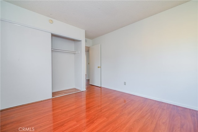 unfurnished bedroom featuring a closet, a textured ceiling, and hardwood / wood-style floors