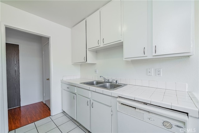 kitchen featuring white cabinets, light tile patterned floors, tile countertops, white dishwasher, and sink