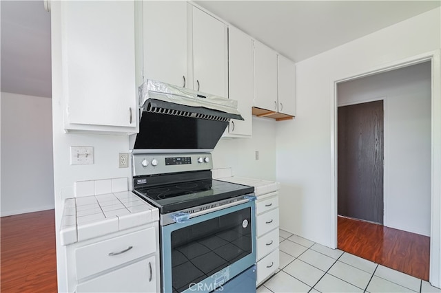 kitchen featuring tile counters, white cabinetry, light wood-type flooring, and electric stove