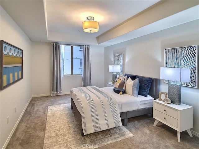 bedroom with a tray ceiling and dark carpet