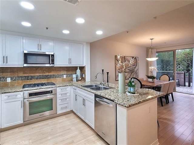 kitchen with white cabinets, stainless steel appliances, kitchen peninsula, and sink