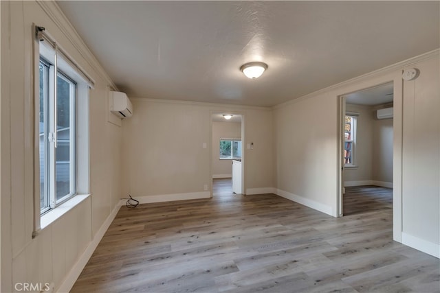 spare room with a textured ceiling, ornamental molding, light hardwood / wood-style flooring, and a wall mounted air conditioner