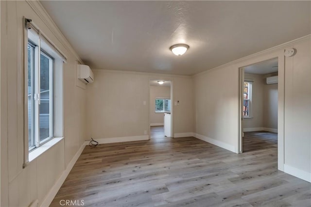 empty room featuring light wood finished floors, an AC wall unit, and ornamental molding