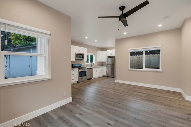 unfurnished living room with light hardwood / wood-style floors, sink, and ceiling fan