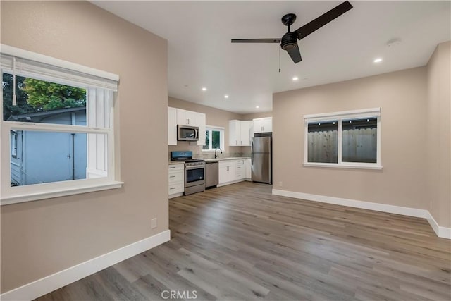 kitchen with white cabinets, light wood finished floors, a wealth of natural light, and stainless steel appliances