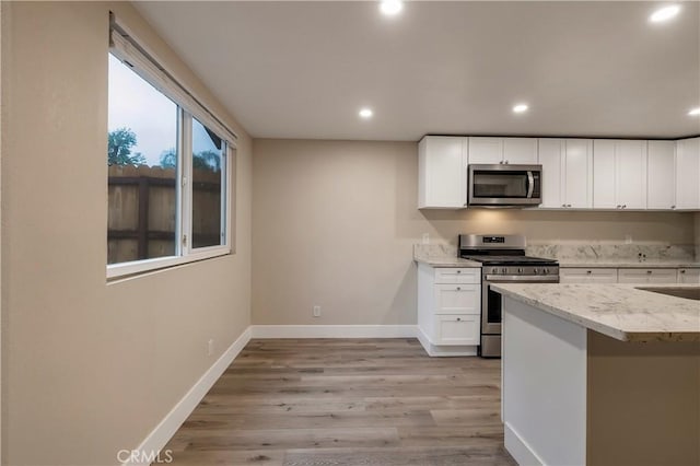 kitchen featuring white cabinets, baseboards, recessed lighting, light stone countertops, and stainless steel appliances