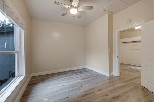 spare room featuring an AC wall unit, ceiling fan, light wood finished floors, and baseboards