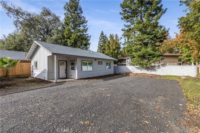 view of front of house featuring board and batten siding, a shingled roof, and fence