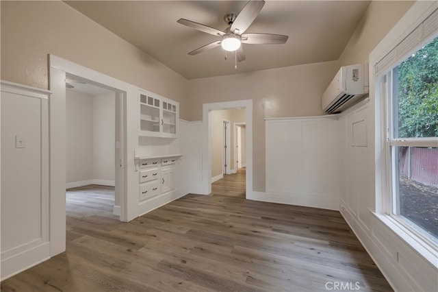 spare room featuring hardwood / wood-style floors, an AC wall unit, and ceiling fan