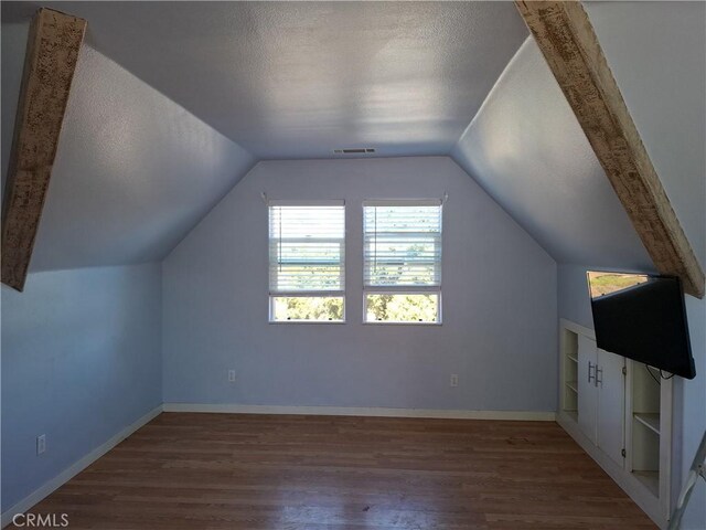 bonus room featuring hardwood / wood-style floors, vaulted ceiling, and a textured ceiling