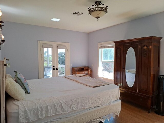 bedroom with access to outside, wood-type flooring, and french doors