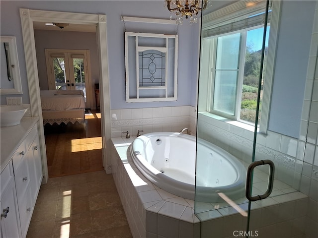 bathroom featuring vanity, tiled bath, hardwood / wood-style flooring, and a chandelier