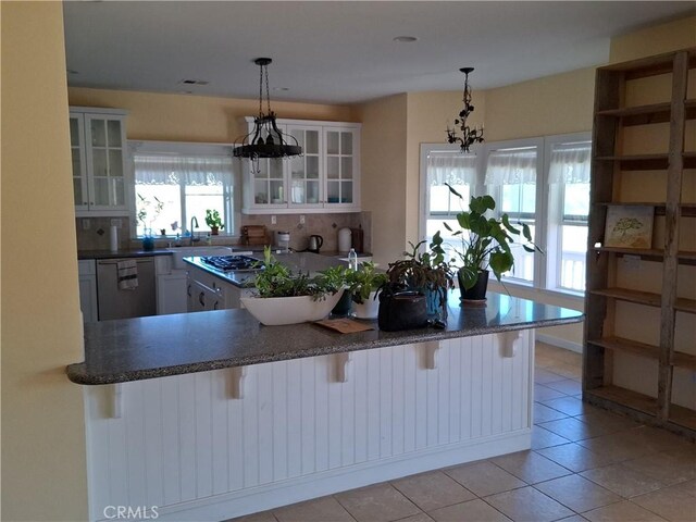 kitchen with dishwasher, a breakfast bar area, pendant lighting, an inviting chandelier, and white cabinets