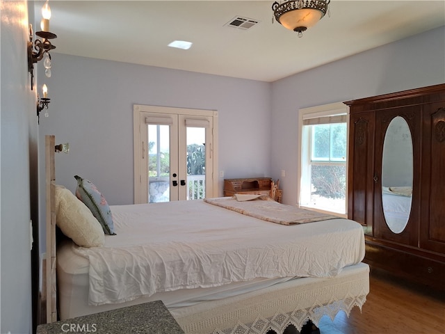 bedroom with hardwood / wood-style floors, multiple windows, access to outside, and french doors