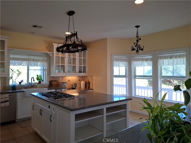 kitchen with stainless steel appliances, backsplash, sink, an inviting chandelier, and white cabinets