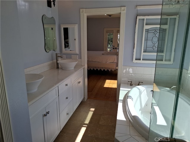 bathroom featuring vanity, wood-type flooring, and tiled bath