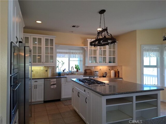 kitchen with white cabinets, backsplash, sink, a notable chandelier, and stainless steel appliances