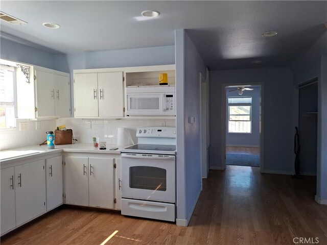 kitchen featuring white appliances, hardwood / wood-style flooring, a healthy amount of sunlight, and white cabinetry