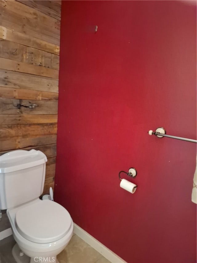 bathroom with toilet, wooden walls, and tile patterned floors