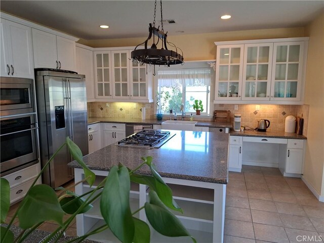 kitchen with backsplash, appliances with stainless steel finishes, a kitchen island, and white cabinets