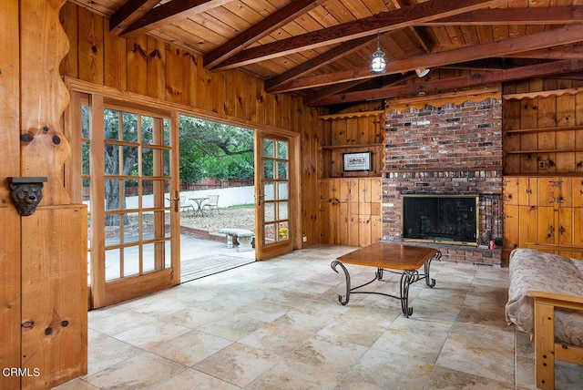 living room featuring beam ceiling, wooden walls, a brick fireplace, and wooden ceiling