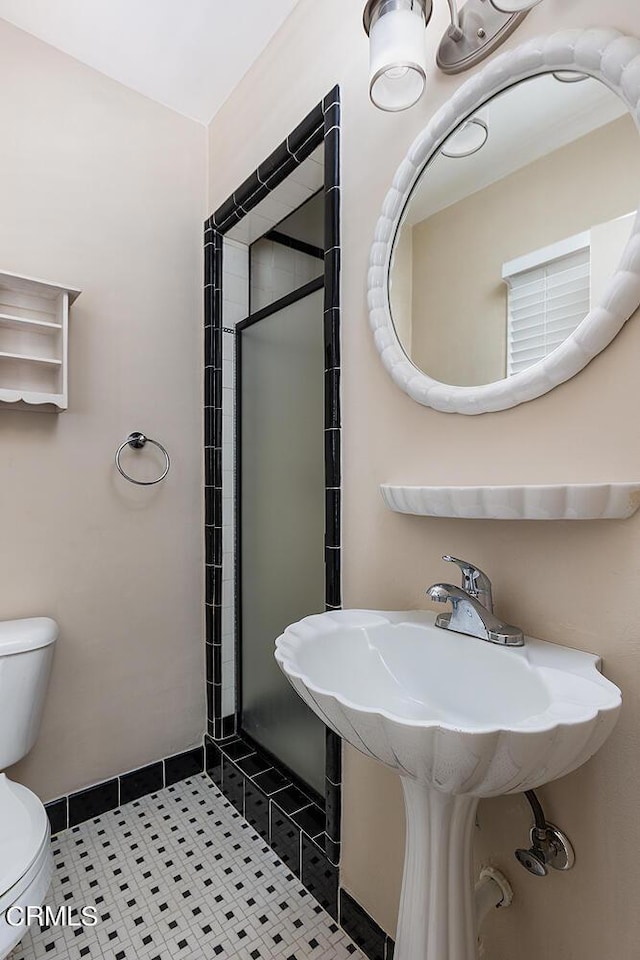 bathroom featuring tile patterned flooring, a shower with shower door, and toilet