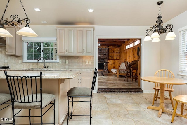 kitchen with pendant lighting, a notable chandelier, light stone countertops, and tasteful backsplash