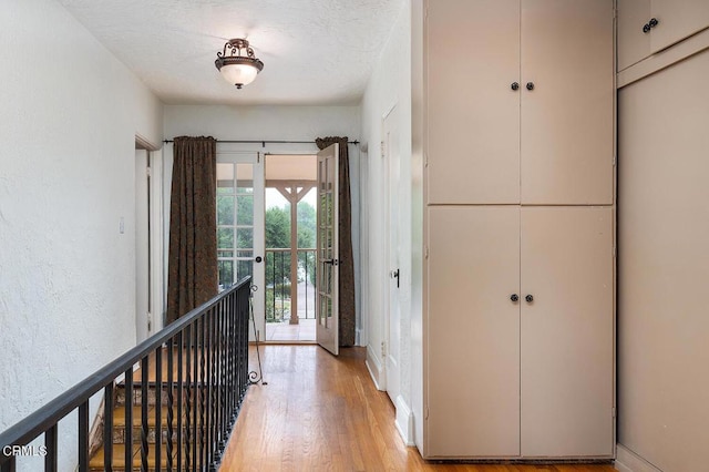 hall with light hardwood / wood-style floors and a textured ceiling