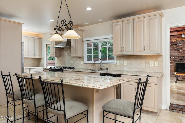 kitchen featuring pendant lighting, a kitchen island, wall chimney range hood, and a wealth of natural light