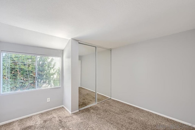 unfurnished bedroom featuring a textured ceiling, carpet floors, and a closet