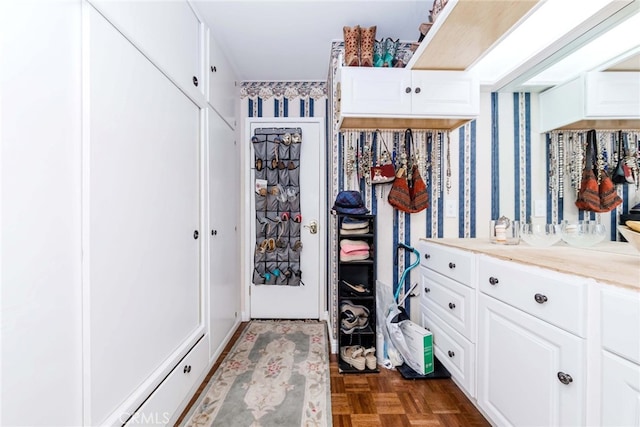 walk in closet with dark parquet flooring