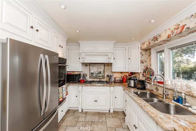 kitchen with white cabinets, light stone countertops, stainless steel appliances, and sink