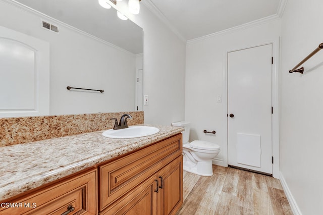 bathroom featuring vanity, hardwood / wood-style floors, ornamental molding, and toilet