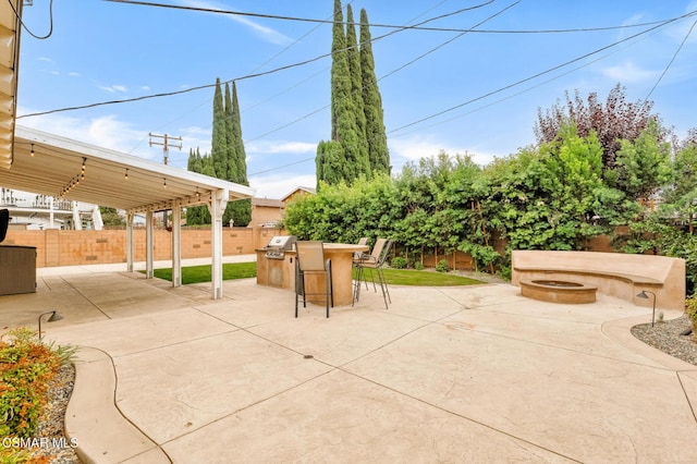 view of patio with an outdoor fire pit, area for grilling, and a bar