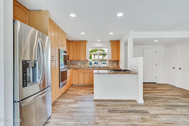 kitchen featuring stone counters, light brown cabinetry, stainless steel appliances, decorative backsplash, and light hardwood / wood-style flooring