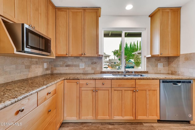 kitchen featuring backsplash, light stone countertops, sink, light hardwood / wood-style floors, and stainless steel appliances