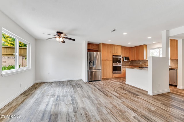 kitchen featuring tasteful backsplash, appliances with stainless steel finishes, and light hardwood / wood-style flooring