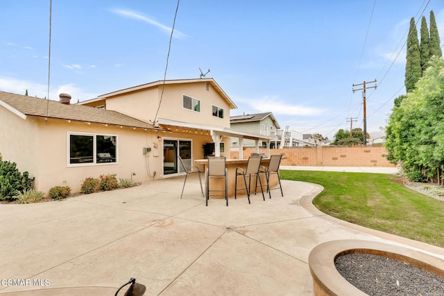 back of house with exterior bar, a patio area, and a lawn