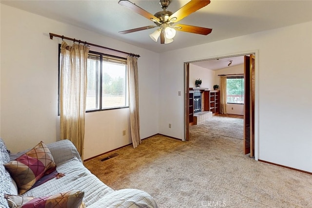 carpeted living room with ceiling fan, vaulted ceiling, and plenty of natural light